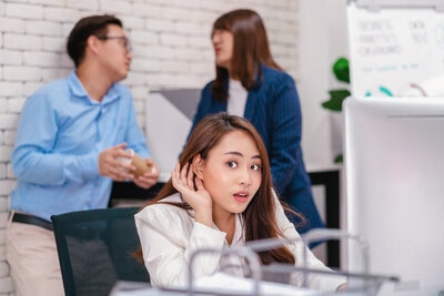 curious businesswoman listening to coworkers gossiping about the company