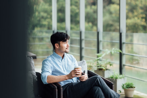 satisfied businessman looking outside the window drinking coffee