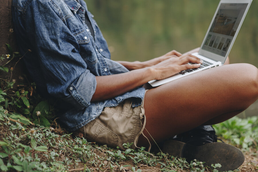 Freelancer working in the forest on her laptop doing gig work