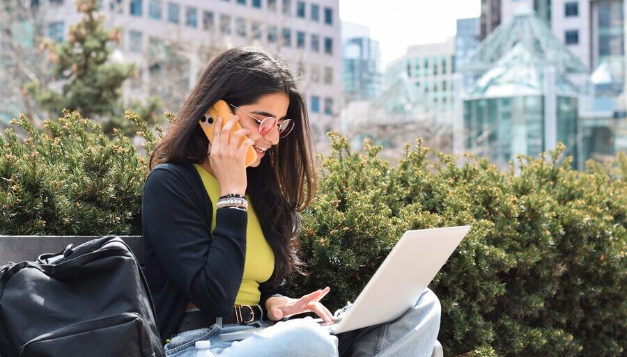 Independent contractor, female gig worker working from a park bench